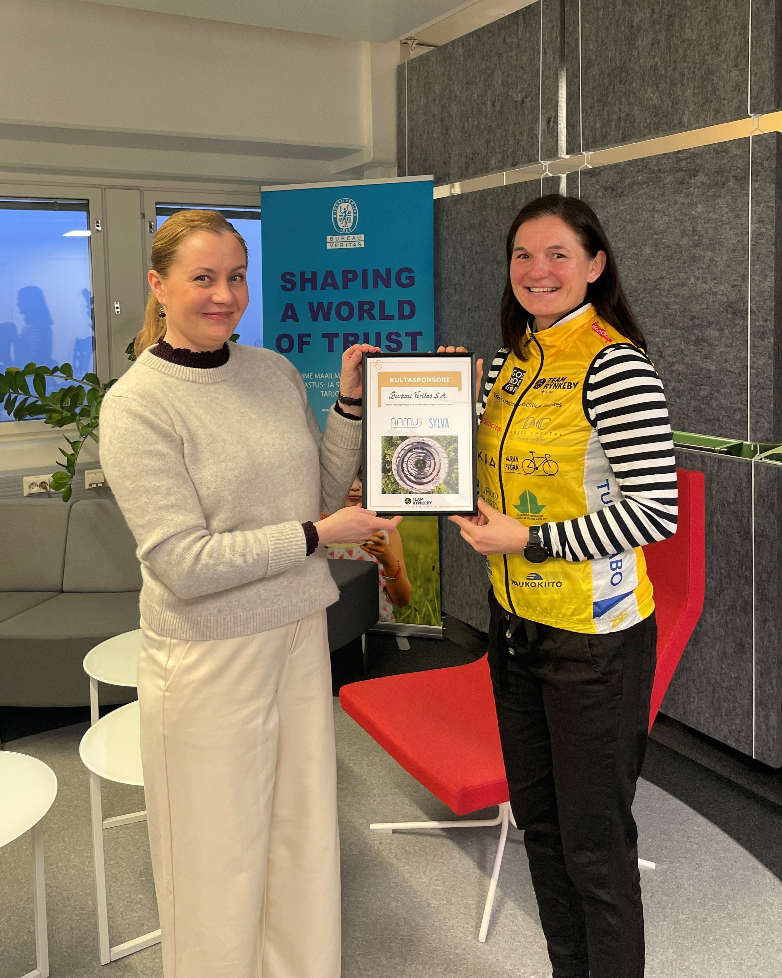 Kuvassa Team Rynkeby pyöräilijä Katri Tuomi ojentamassa kunniakirjaa Bureau Veritkasen I&F Manger Salla Punkarille