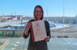 A woman holding a certificate from ISO 9001 course